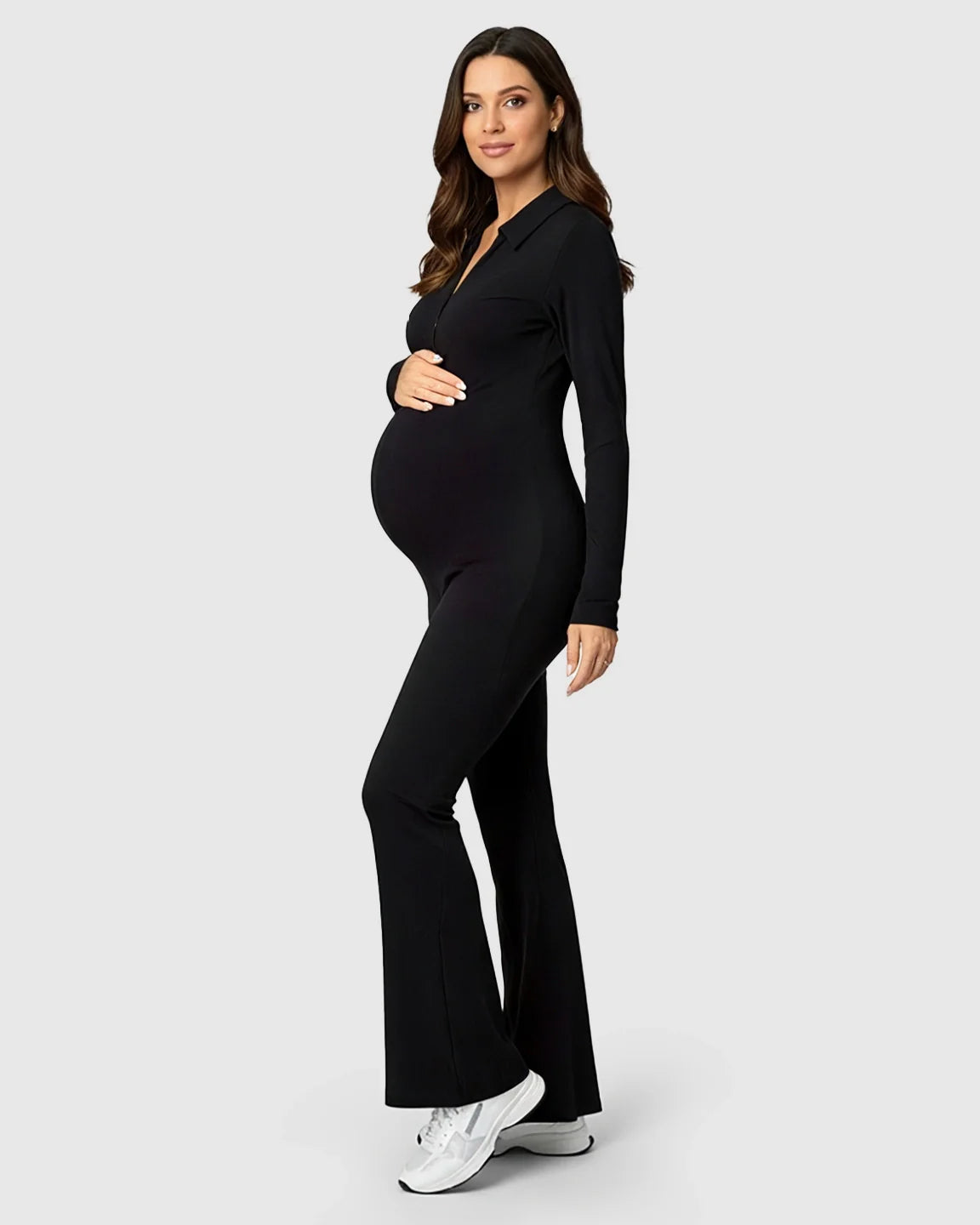 Pregnant woman in a black ribbed, zip-front maternity jumpsuit with flared legs.