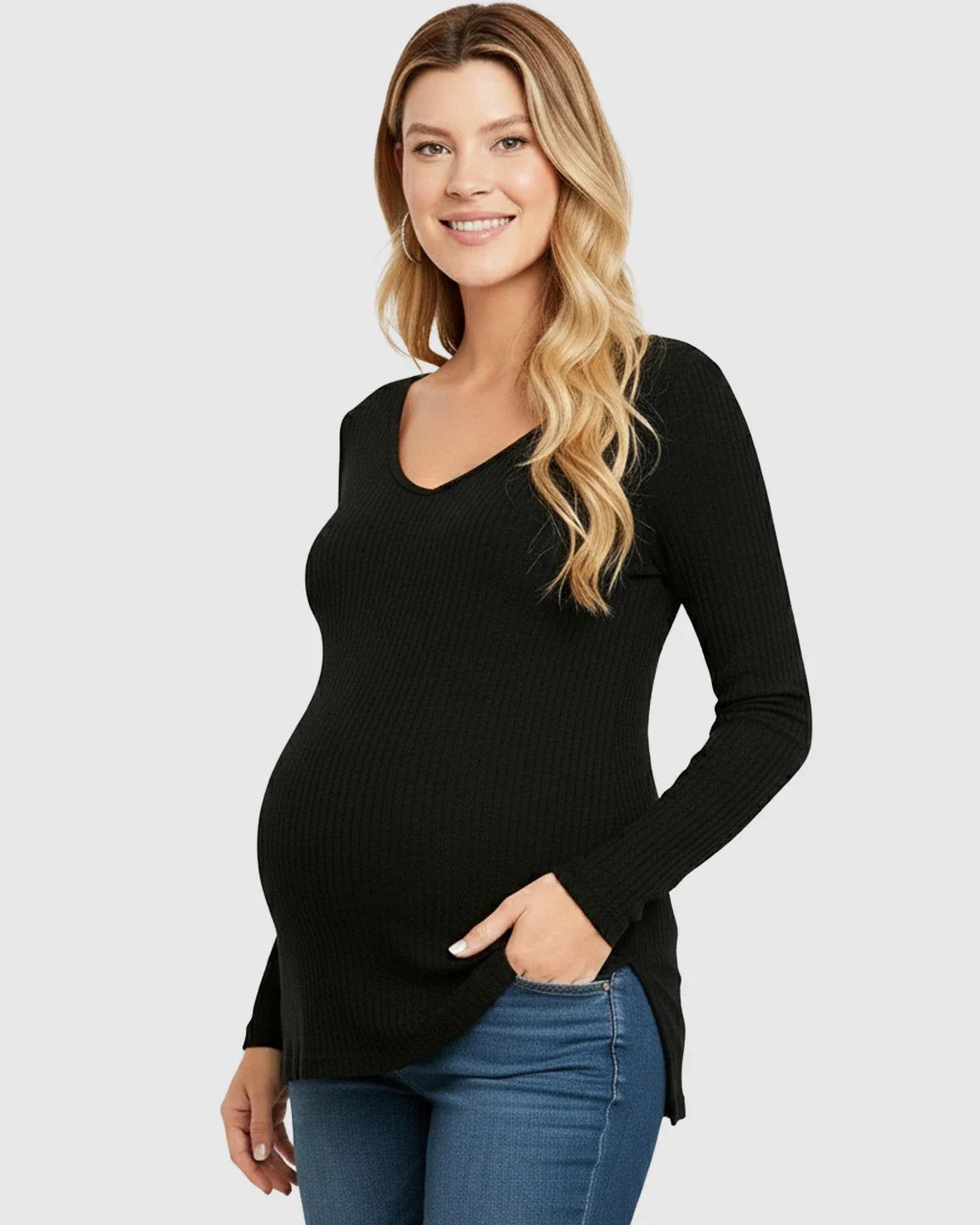 Smiling pregnant woman wearing a black ribbed V-neck long sleeve maternity top with side slits and blue jeans.