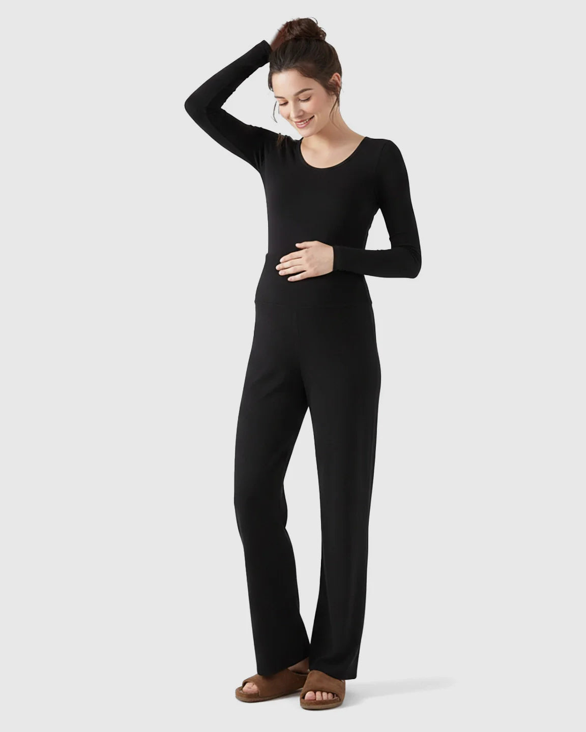 Woman in black fleece relaxed maternity pants with over-belly waistband and wide-leg silhouette.