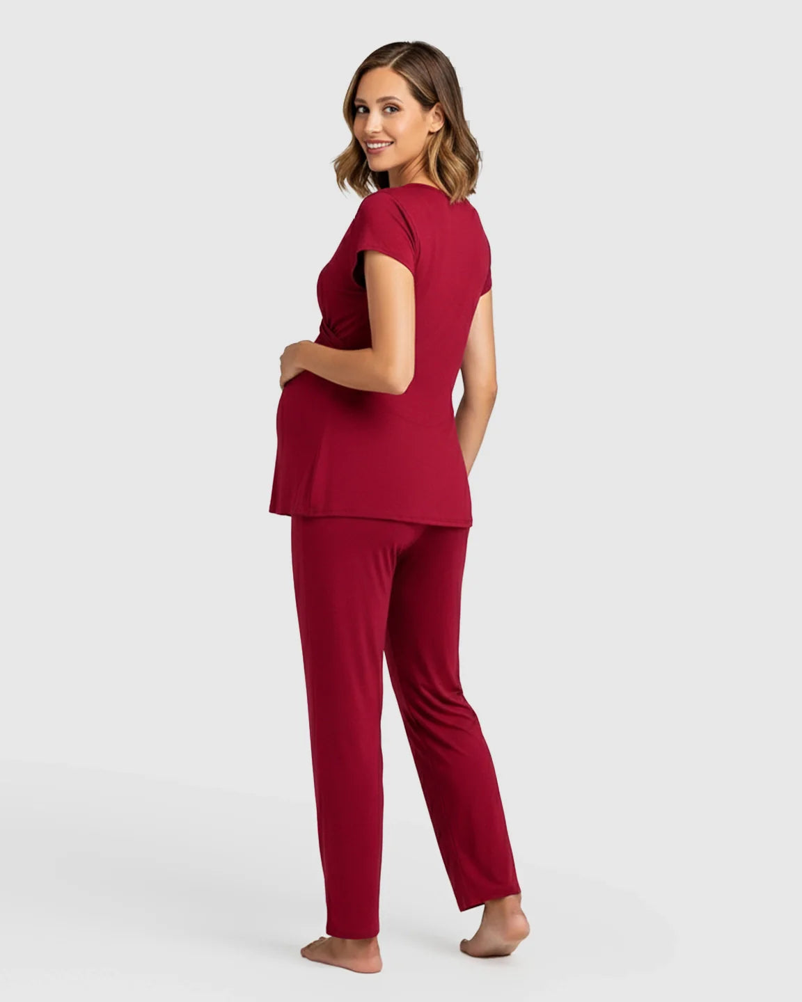 Pregnant woman in a red short-sleeve wrap top and matching pants maternity & nursing sleepwear set.