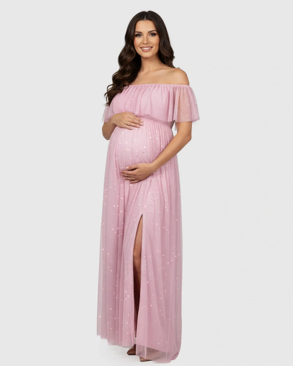 Smiling pregnant woman in a pink off-shoulder mesh slit maternity gown with glitter details.