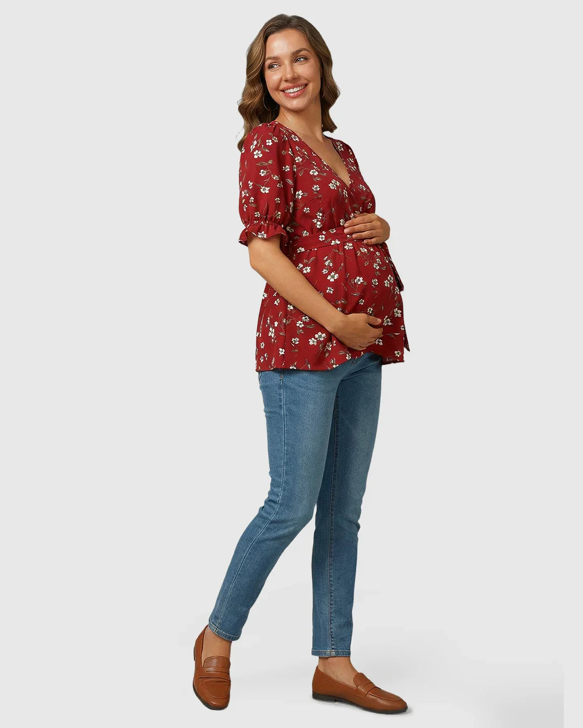 Smiling pregnant woman in a red floral crossover V-neck maternity and nursing top with puff sleeves.