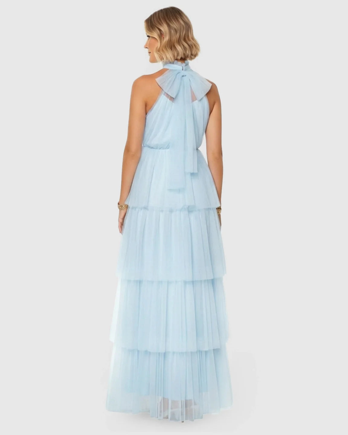 Woman in a light blue halter neck tiered mesh maternity gown with a back bow detail.