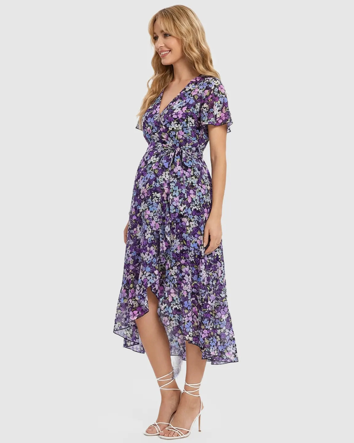 Smiling pregnant woman in a purple floral V-neck ruffled hem maternity midi dress.