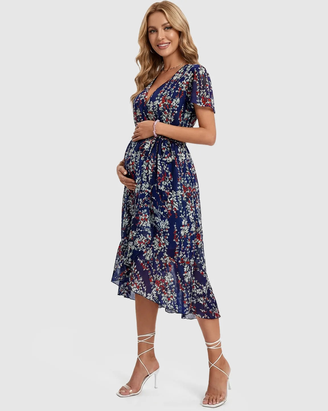 Smiling pregnant woman in a navy floral V-neck maternity midi dress with ruffled hem.
