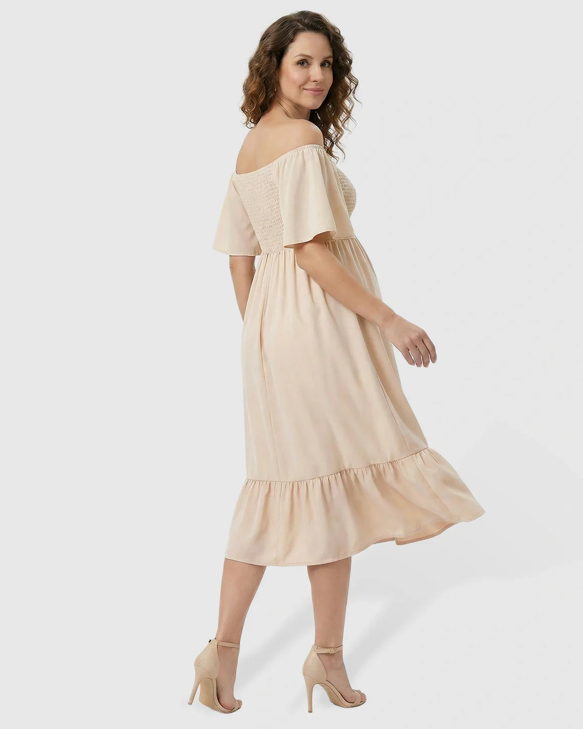 Maternity midi dress in light peach with off-shoulder smocked top, flutter sleeves, and tiered flowy skirt.