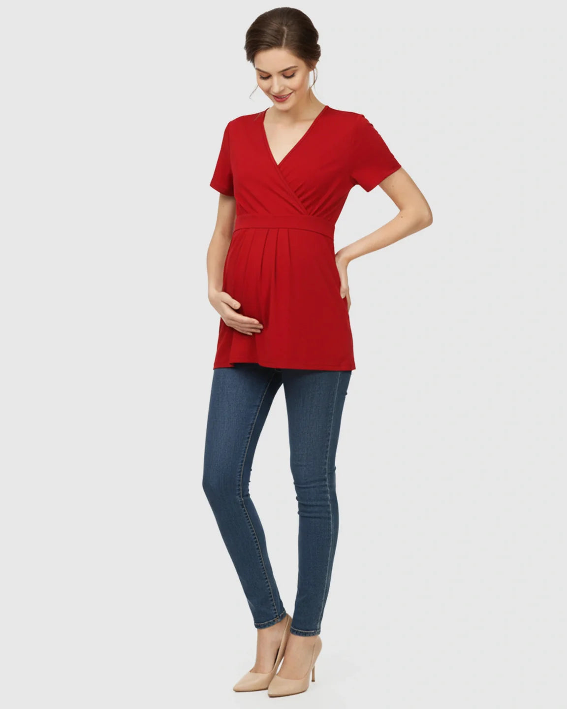 Pregnant woman in a red V-neck wrap-style maternity top with an adjustable waist tie, paired with jeans.