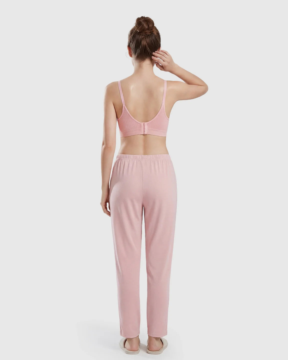 Woman from behind wearing a pink seamless wireless nursing bra and matching pink lounge pants.