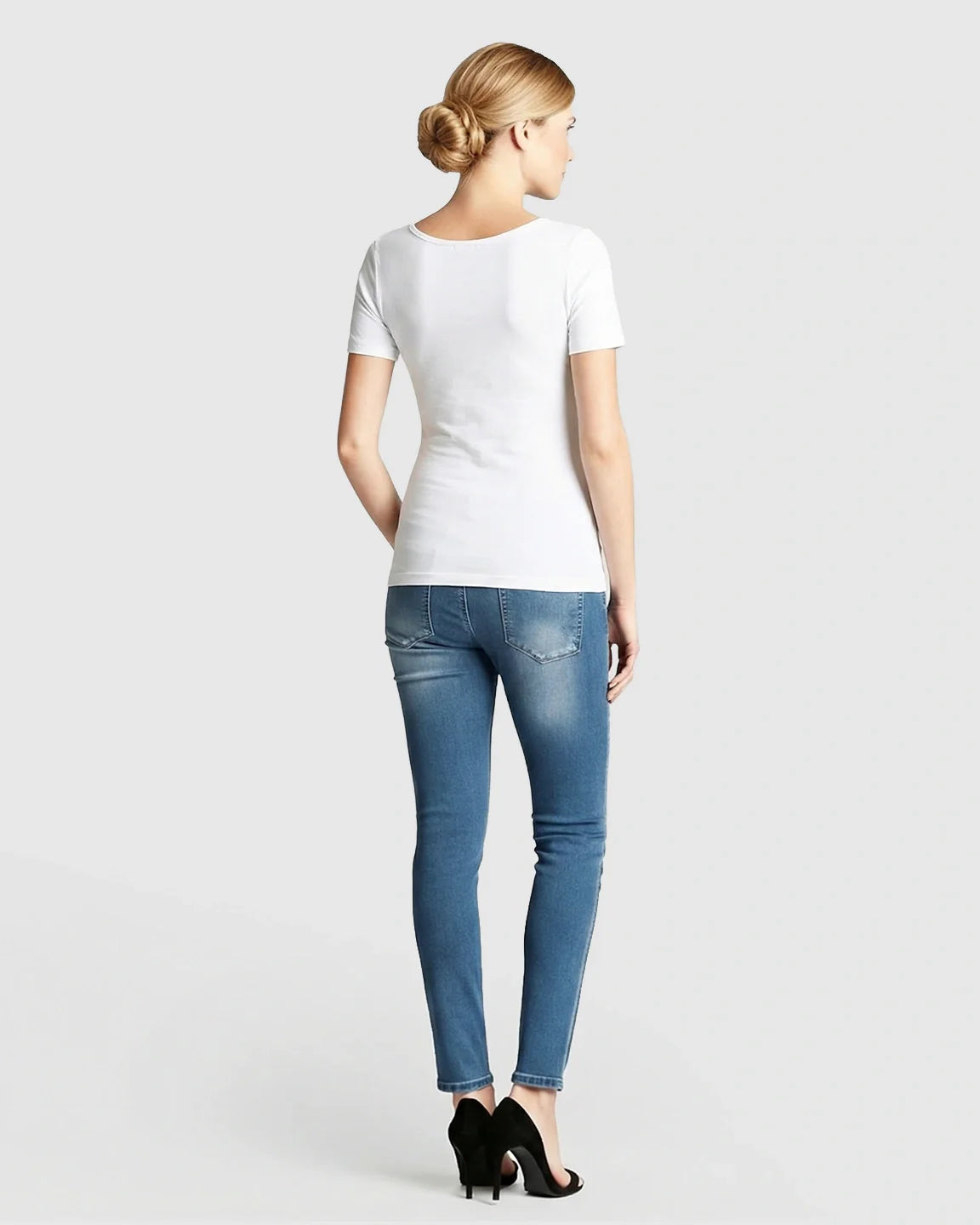 Woman from behind wearing a white stretch-fit V-neck nursing t-shirt and blue jeans.