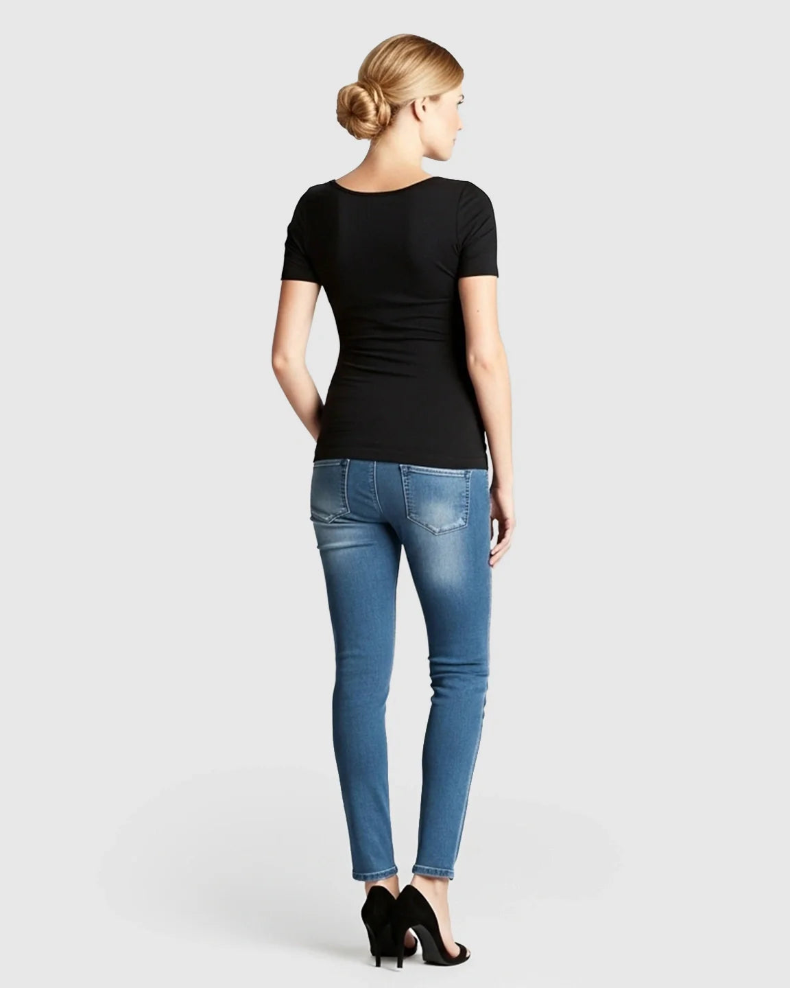 Woman from behind wearing a black stretch-fit V-neck nursing t-shirt and blue jeans.