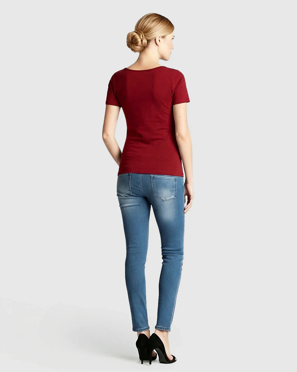 Woman from behind wearing a red stretch-fit V-neck nursing t-shirt and blue jeans.