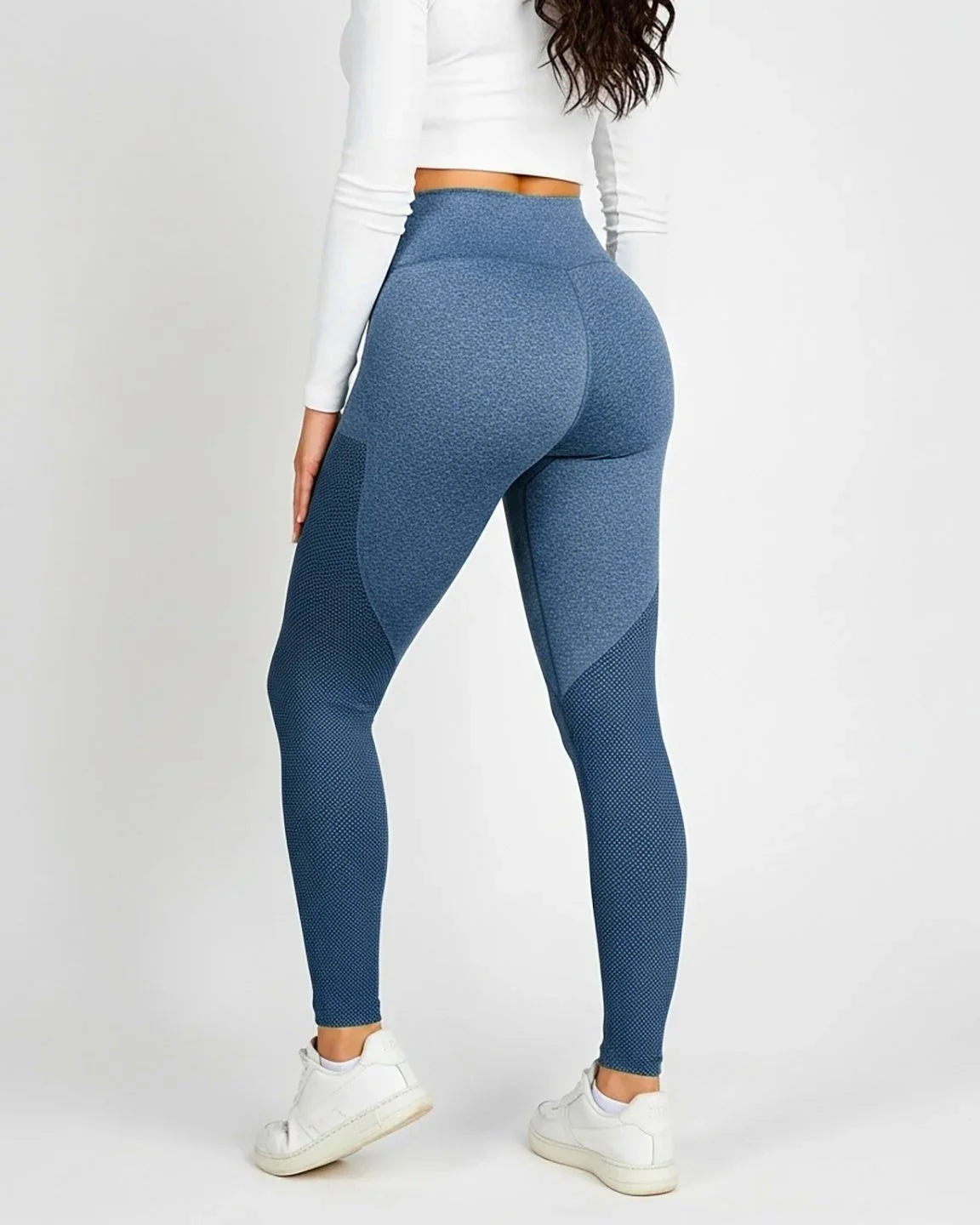 Woman in blue high-elastic, body-hugging maternity leggings with mesh panels, paired with a white crop top.