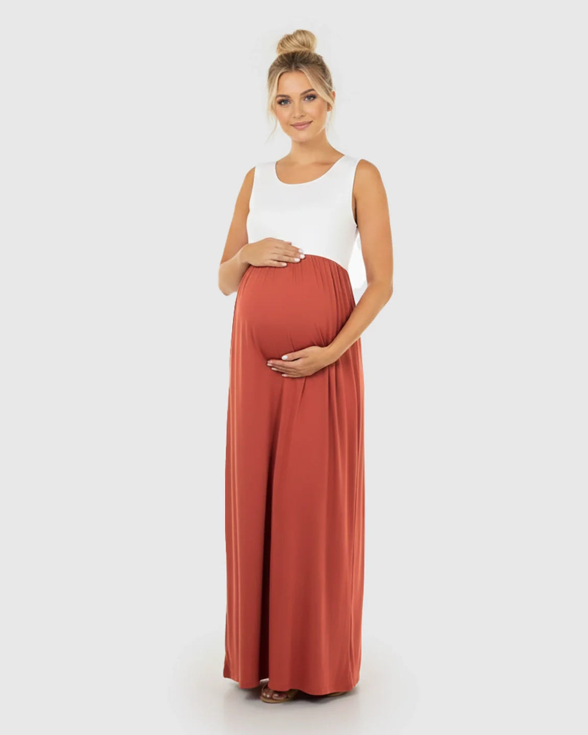 Smiling pregnant woman in a white and rust colorblock high-waisted maternity maxi dress.