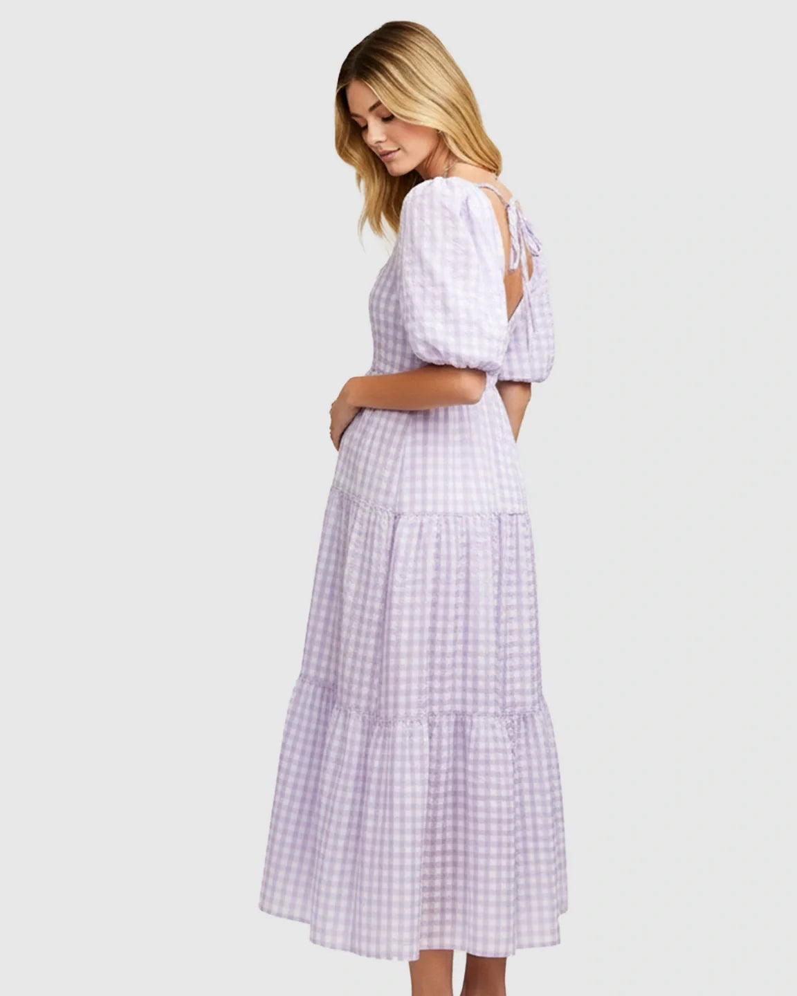 Blonde woman in a lavender and white checkered maternity maxi dress with puffed sleeves and a tie-back.