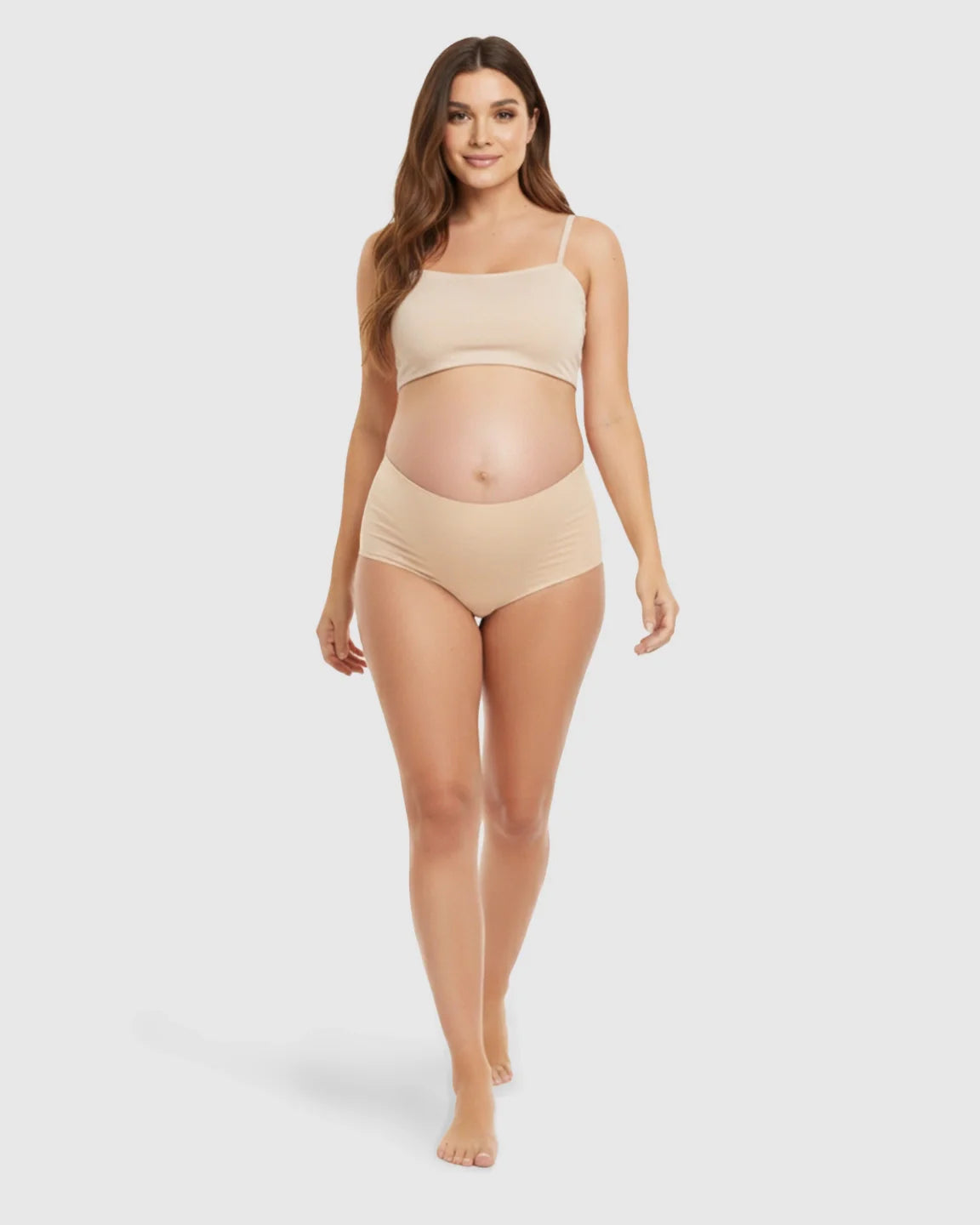 Smiling pregnant woman models seamless high-waist nude maternity support underwear and matching bra.