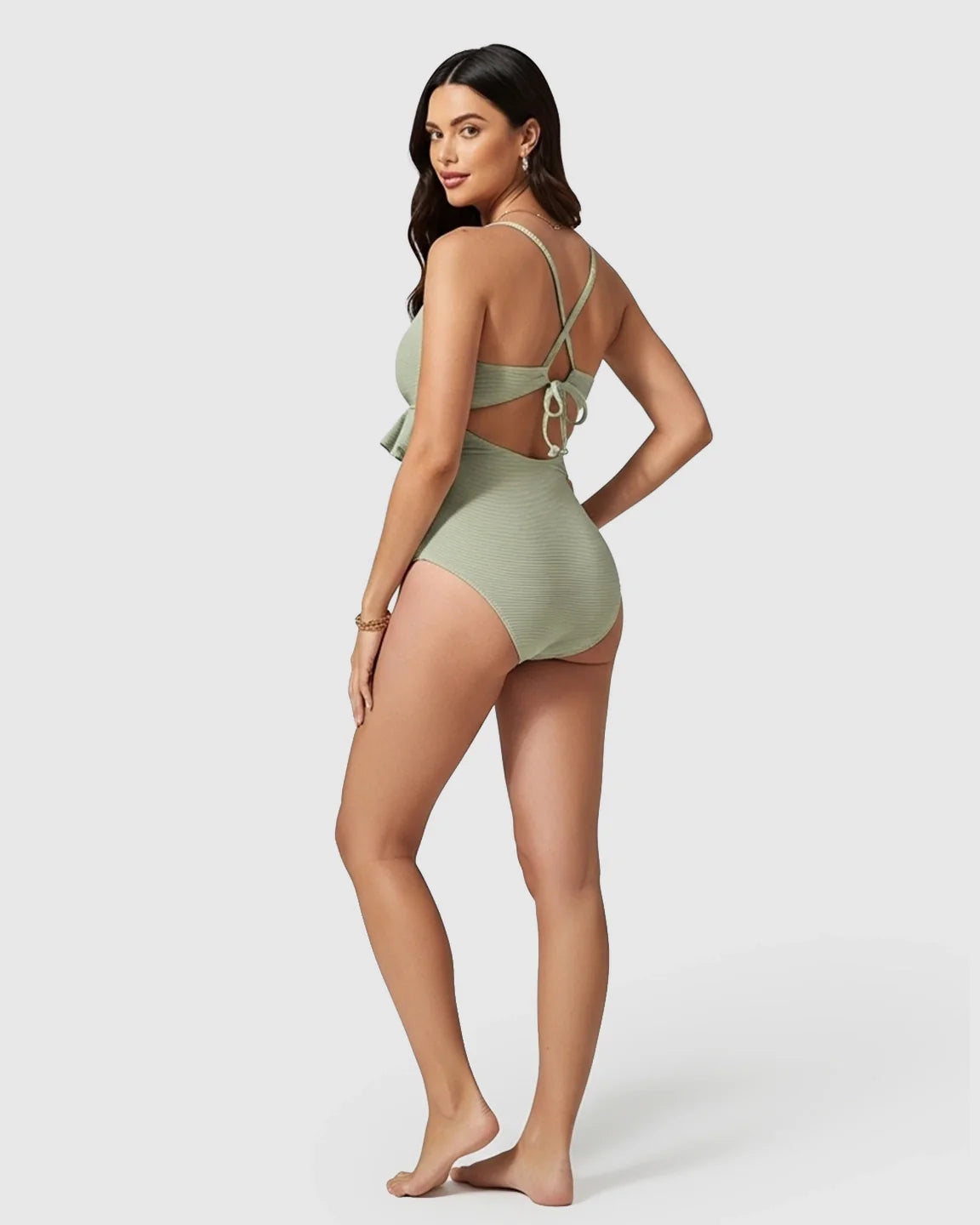 Model in a sage green ribbed tankini maternity swimsuit with ruffle detail and crisscross back straps.