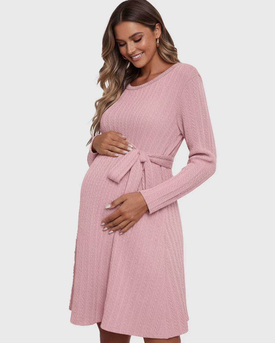 Smiling pregnant woman in a pink ribbed tie-waist maternity midi dress with long sleeves.