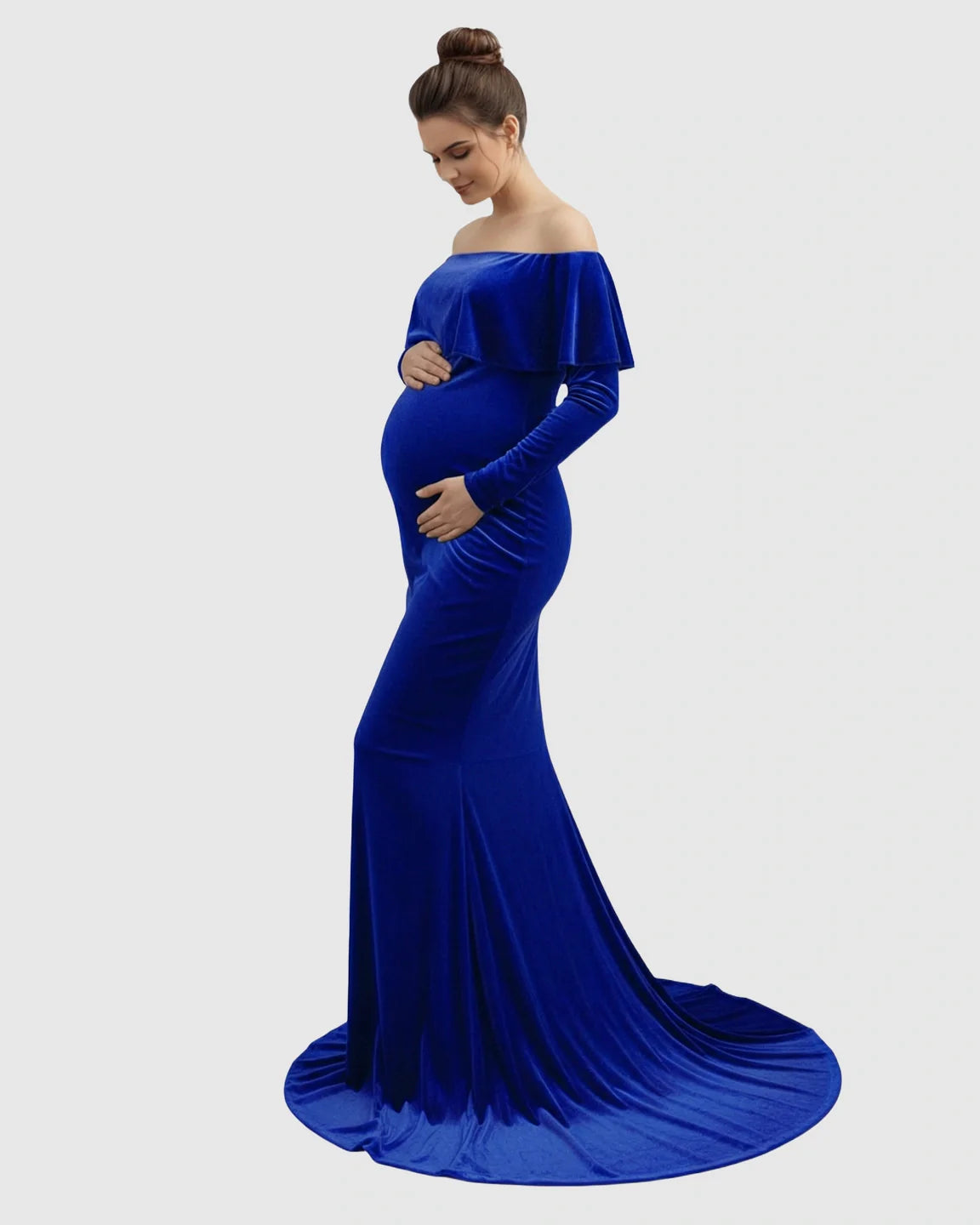 Pregnant woman in a royal blue velvet off-shoulder fitted gown with a flowing train, cradling her bump.