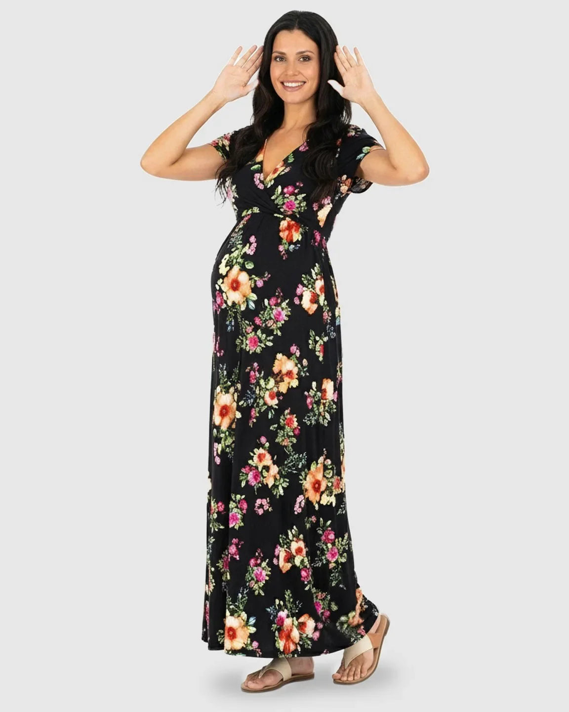 Smiling pregnant woman in a black floral V-neck short sleeve maternity maxi dress with colorful flowers.