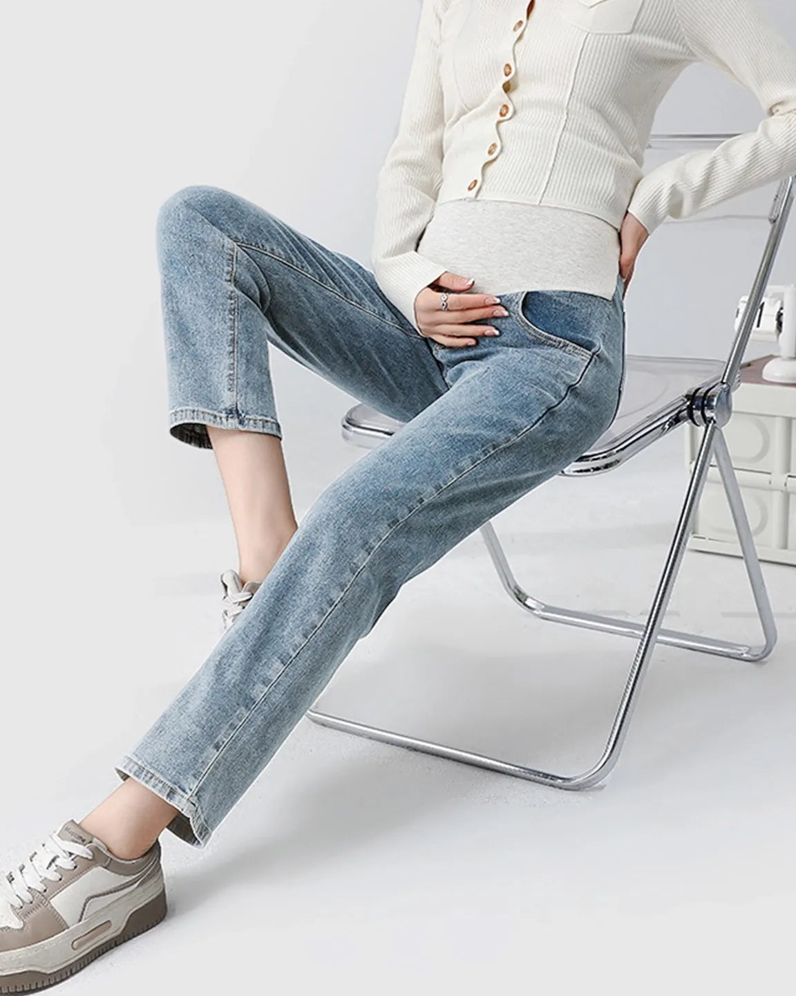 Light wash straight-leg maternity jeans with a supportive belly band, worn by a pregnant woman sitting.