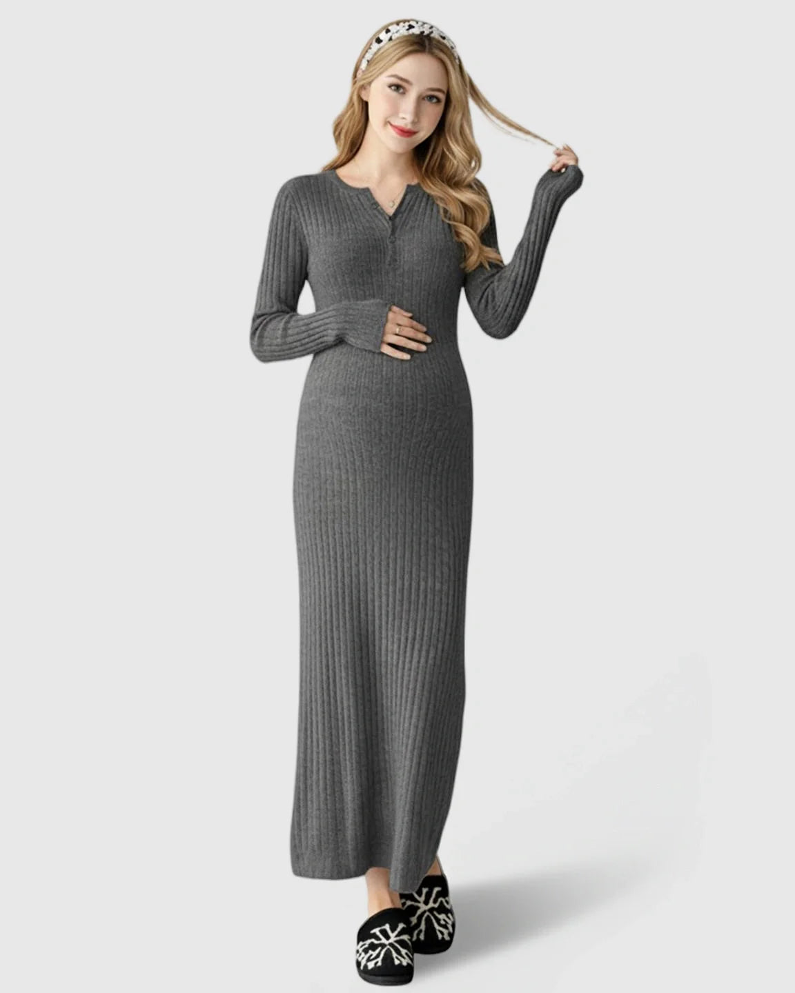 Pregnant woman in a gray ribbed knit A-line long sleeve maternity maxi dress, holding her belly.