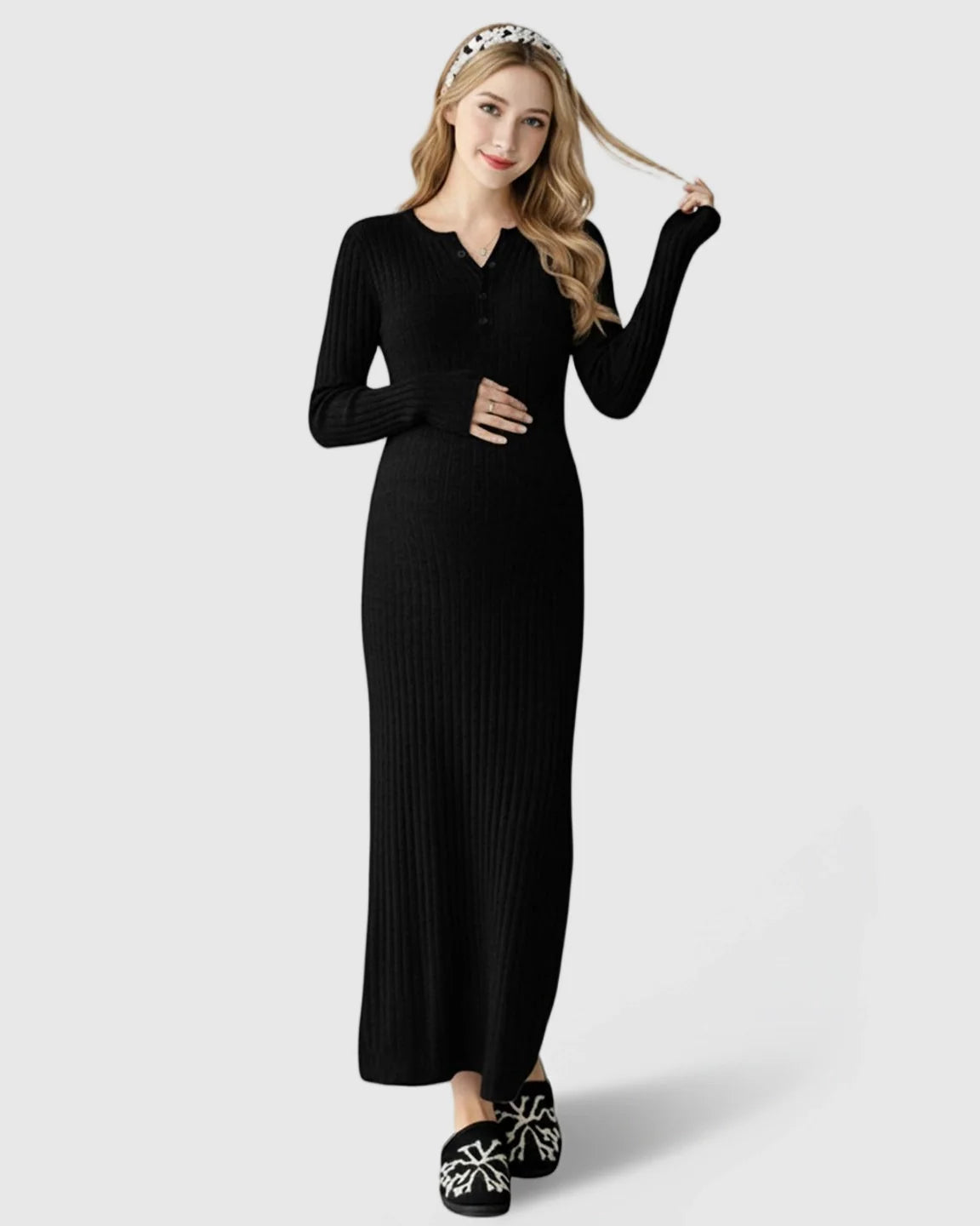 Pregnant woman in a black ribbed knit A-line long sleeve maternity maxi dress, touching her belly.