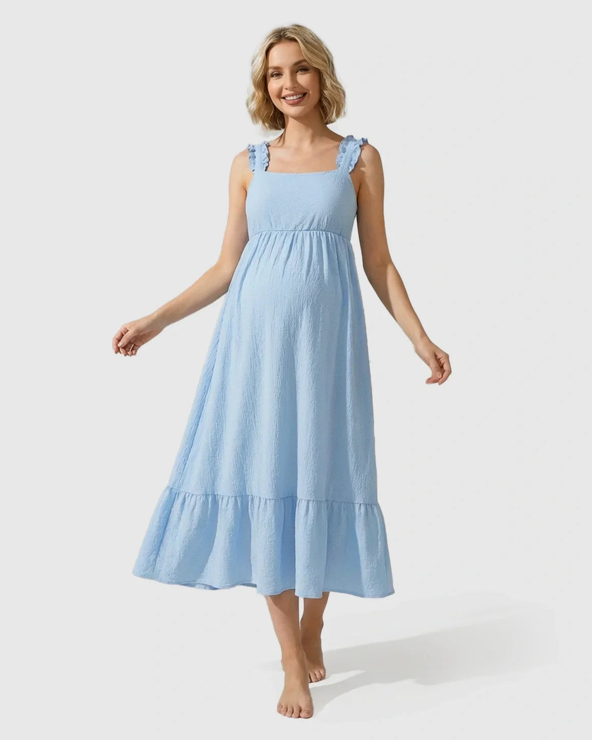 Smiling pregnant woman in a light blue ruffled strap tiered maternity maxi dress.