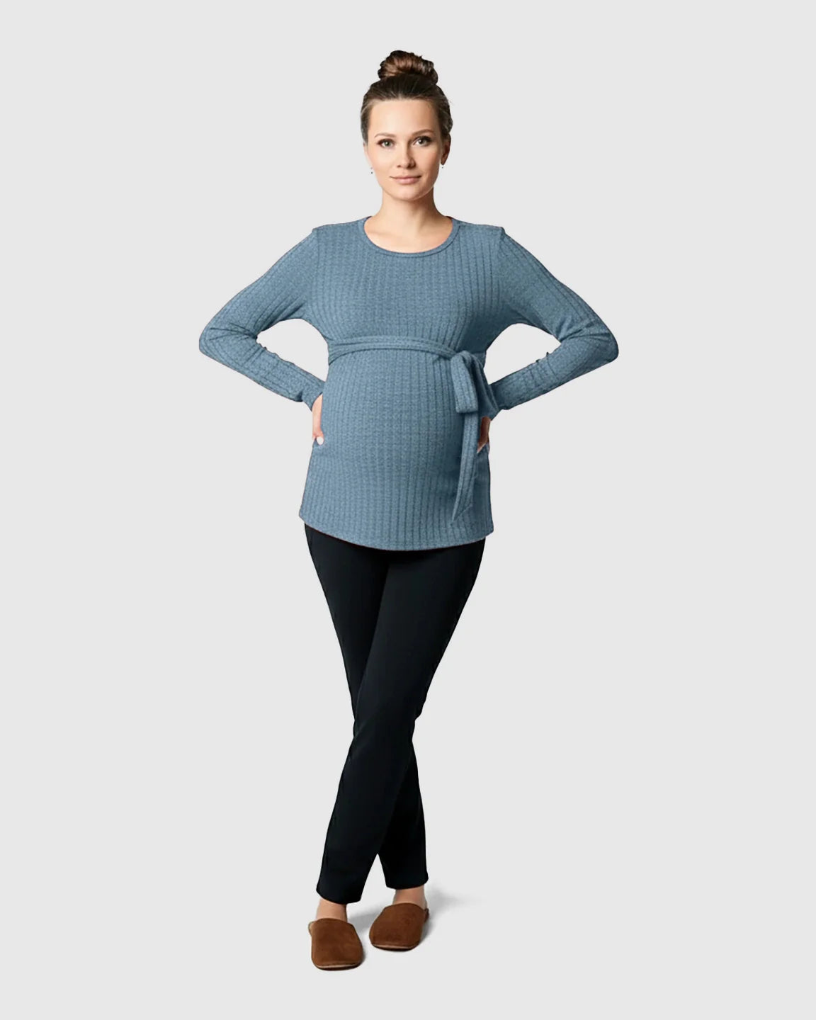 Pregnant woman in a blue ribbed tie-waist long sleeve maternity sweater and black pants.