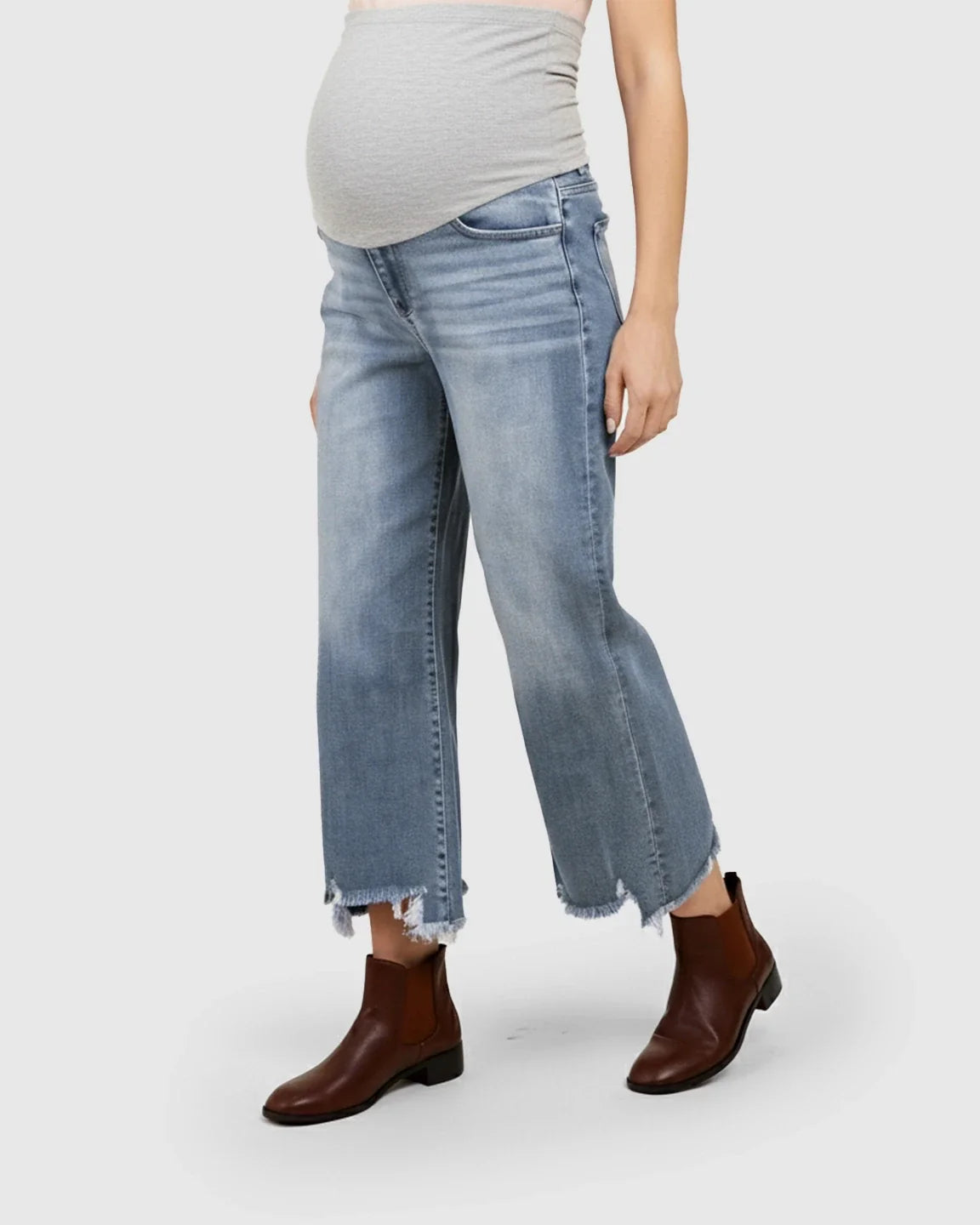 Light wash wide-leg maternity jeans with a grey belly panel and raw hem, paired with brown boots.