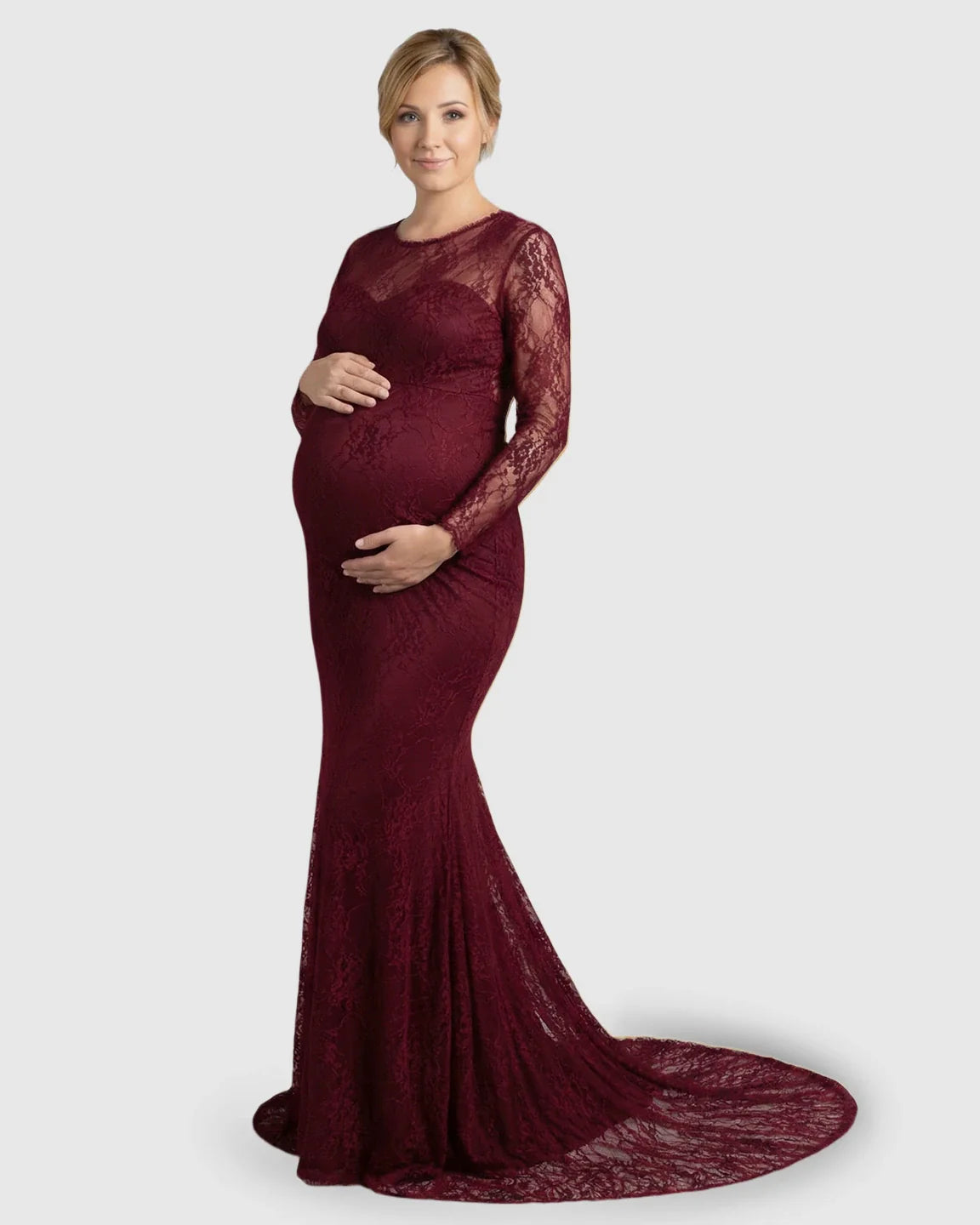 Pregnant woman in a long-sleeved, sheer burgundy lace trumpet maternity gown with a mermaid-style skirt.