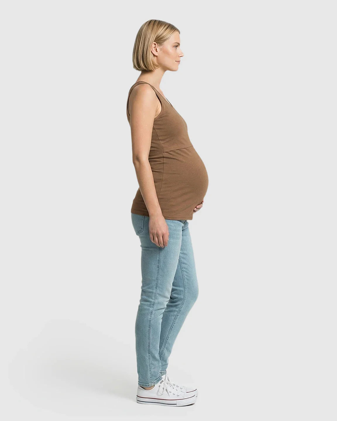 Pregnant woman in a brown stretch nursing-access maternity tank top and light wash jeans.