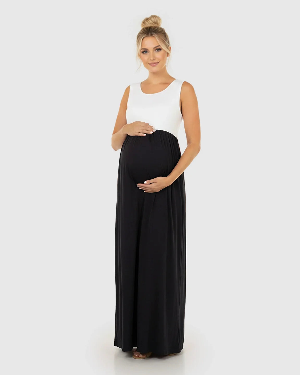 Pregnant woman in a white and black colorblock high-waisted maternity maxi dress with a round neck.