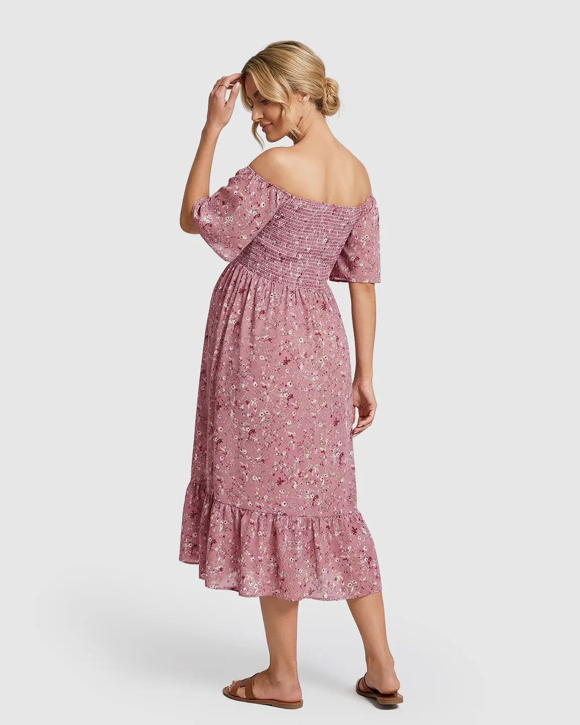 Pink floral flutter-sleeve smocked maternity midi dress with tiered skirt, worn by a woman facing away.