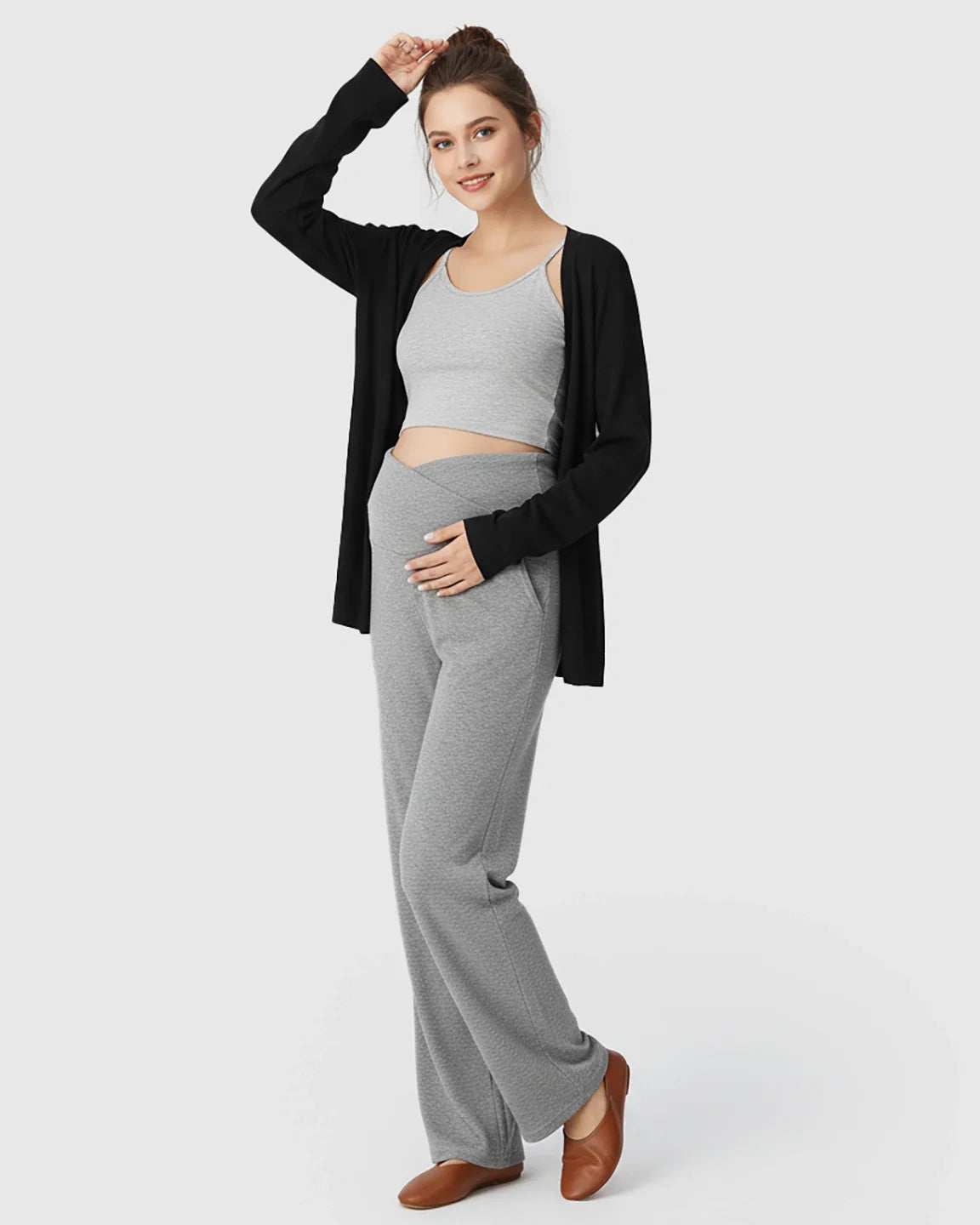 Pregnant woman in gray crossover waist wide-leg maternity lounge pants, gray crop top, and black cardigan.