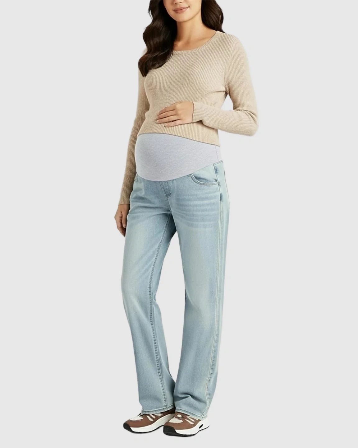 Pregnant woman in light wash, straight-leg maternity jeans with a grey belly band and a beige sweater.