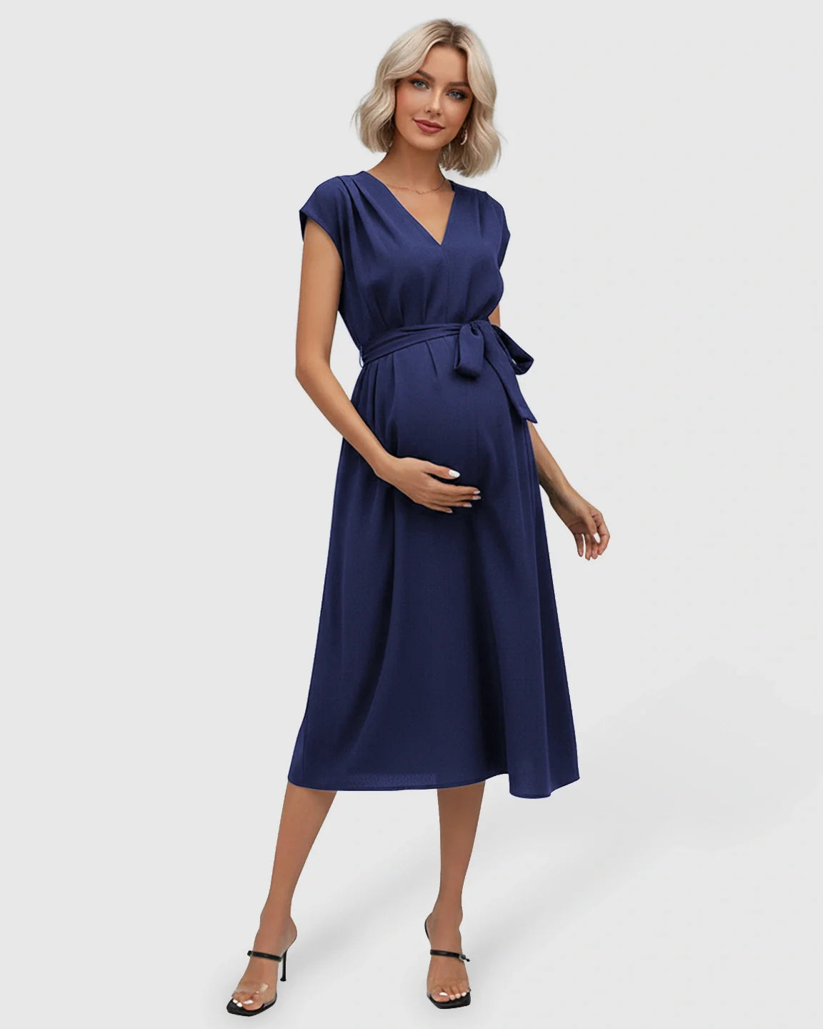 Pregnant woman in a navy blue V-neck maternity midi dress with flutter sleeves and an adjustable tie-waist.