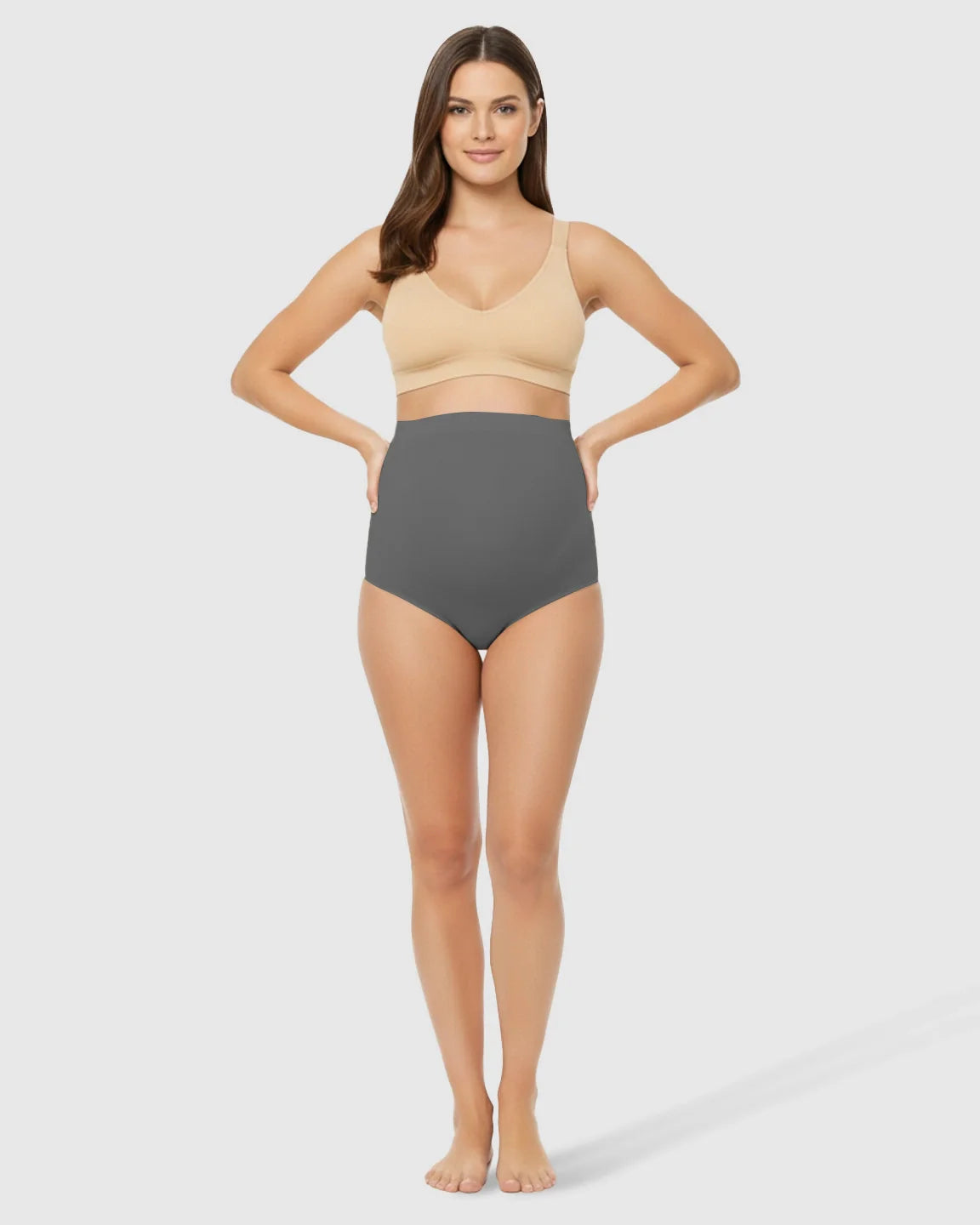 Woman models gray high-waist seamless maternity underwear with belly support, paired with a nude bra.