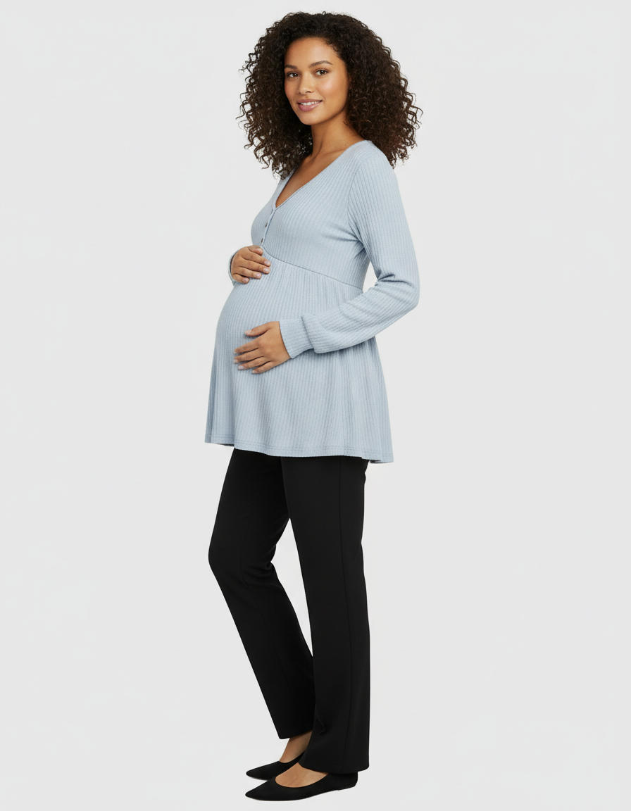 Smiling pregnant woman in a light blue ribbed long-sleeve maternity top and black pants.
