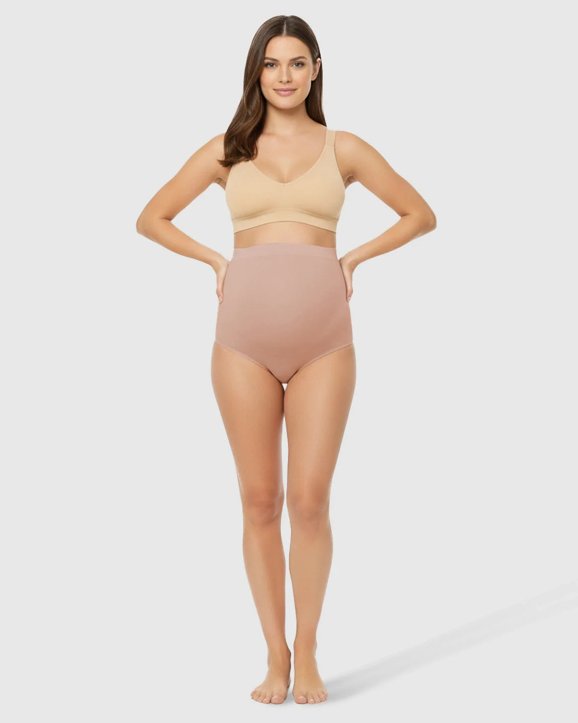 Woman modeling seamless high-waist nude maternity underwear and matching bra, offering gentle belly support.