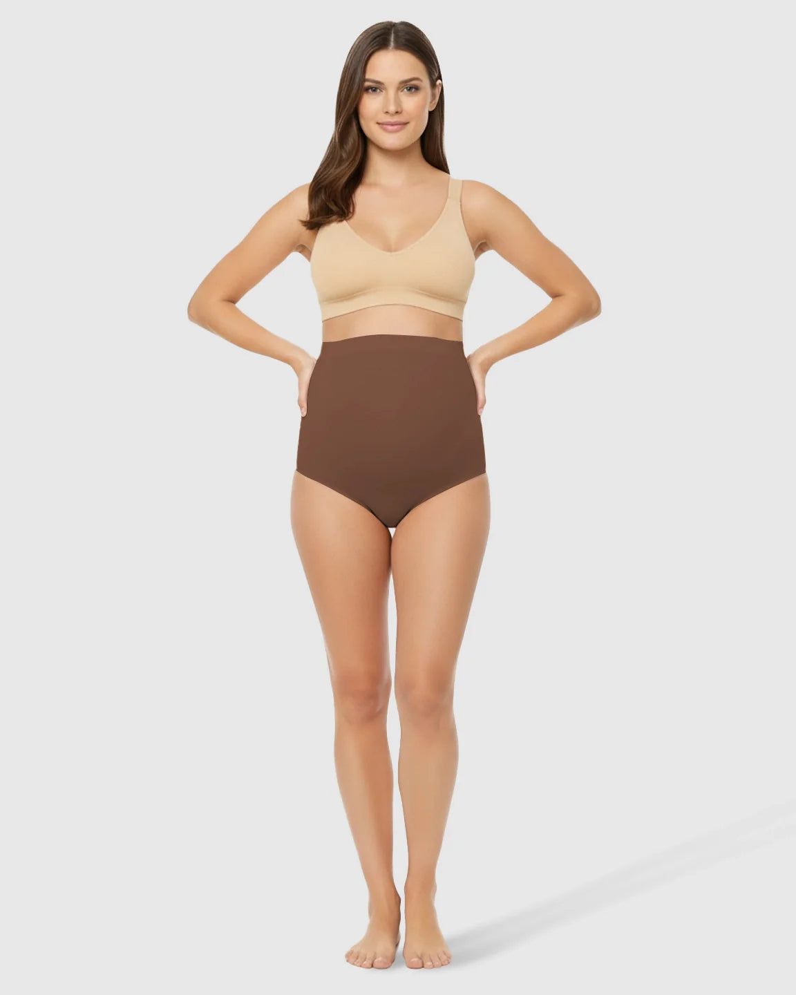 Smiling woman models seamless, high-waist brown maternity underwear with gentle belly support and a nude bra.