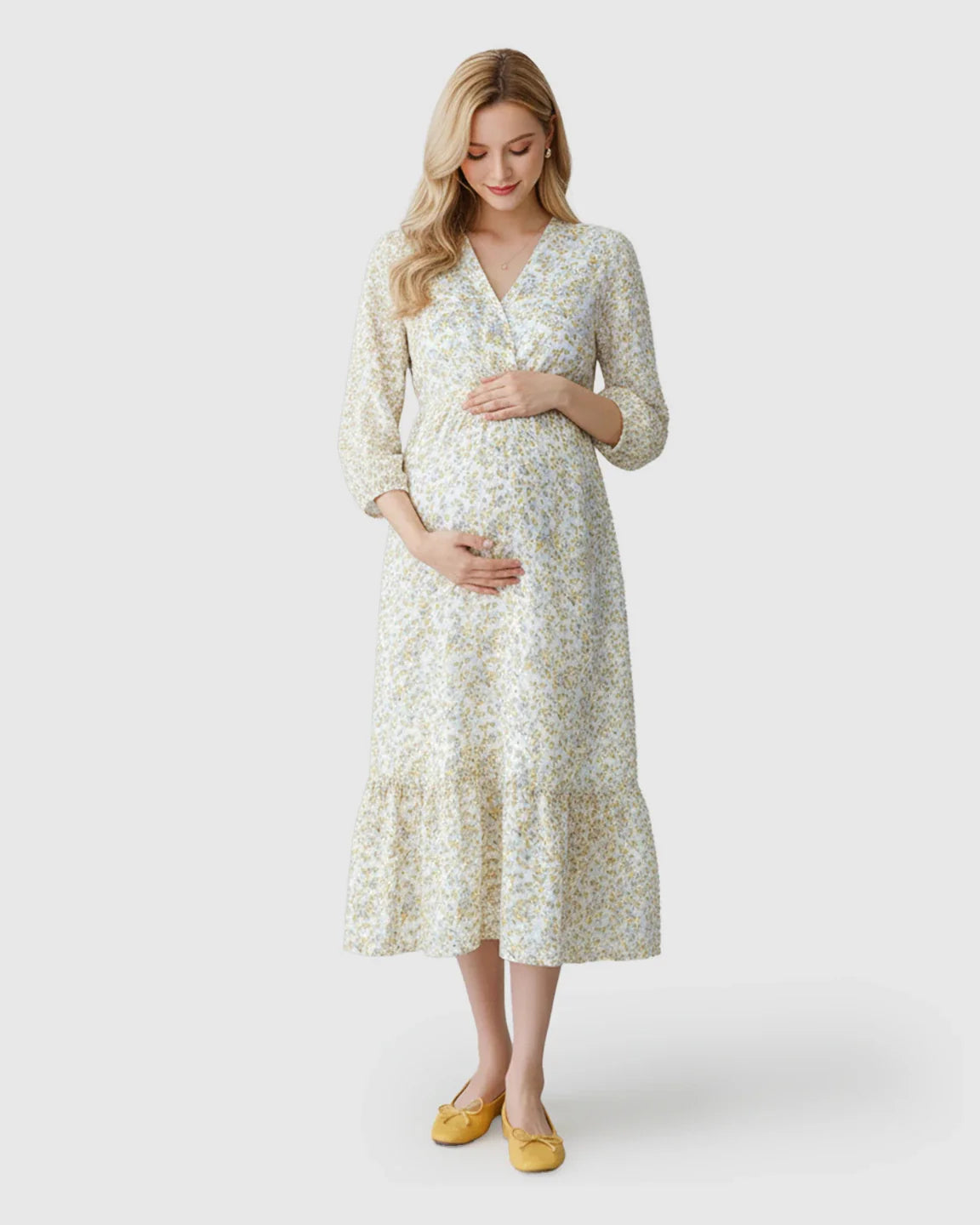 Blonde pregnant woman in a white floral print maternity midi dress with smocked waist and ruffle hem.