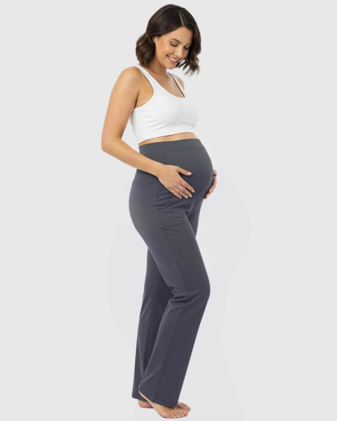 Smiling pregnant woman in charcoal gray stretch flared maternity pants with an over-belly waistband.