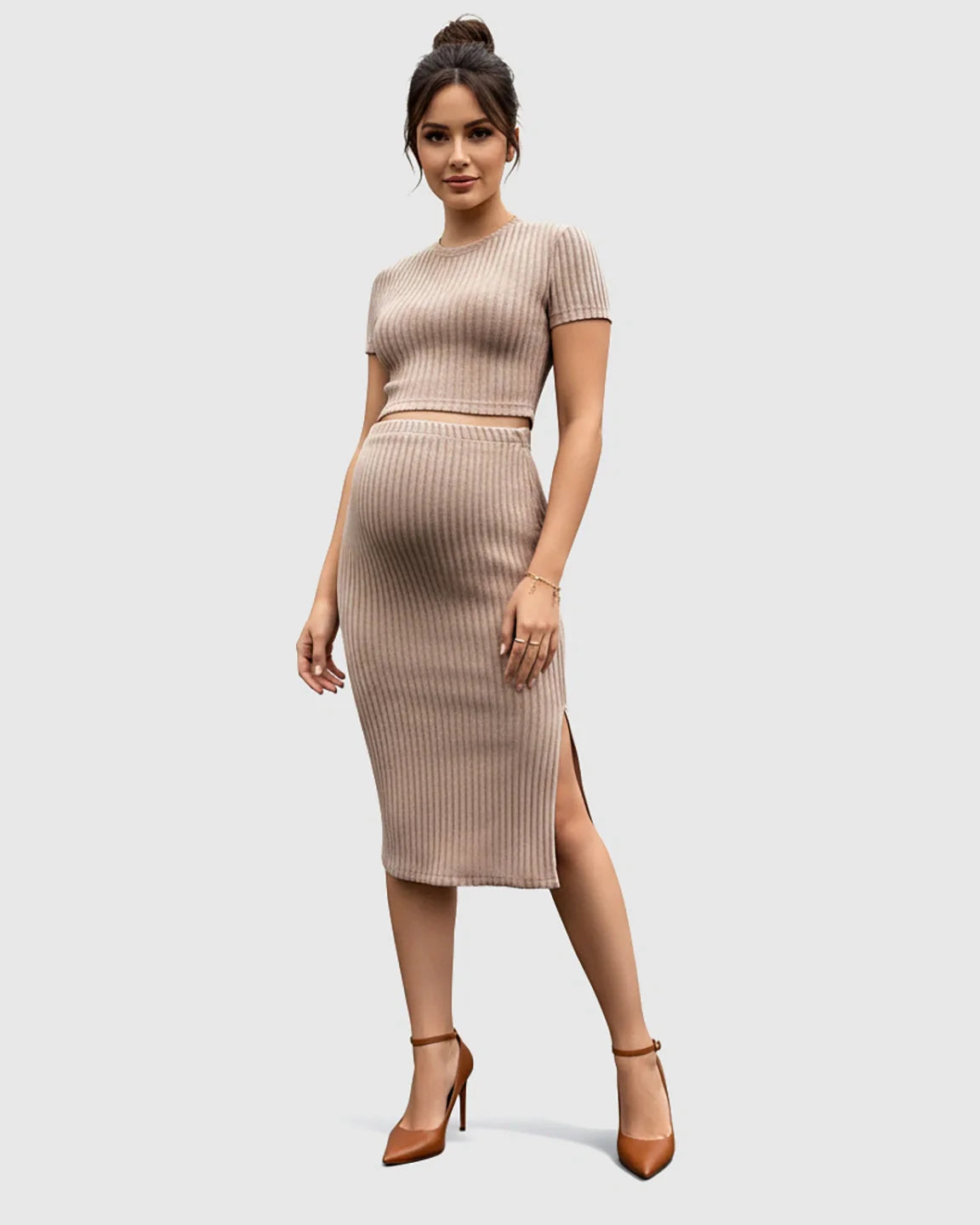 Pregnant woman in a beige ribbed crop top and side-slit bodycon maternity skirt set.