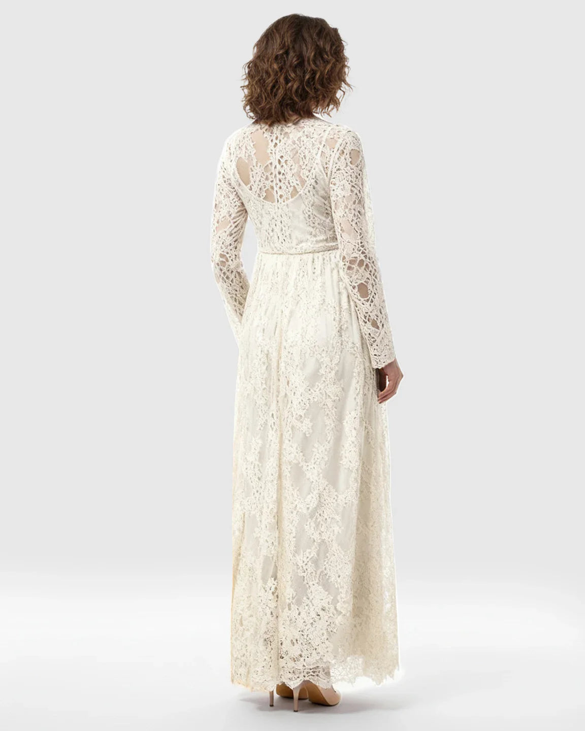 Back view of a pregnant woman in a cream sheer floral lace empire waist maternity maxi dress.