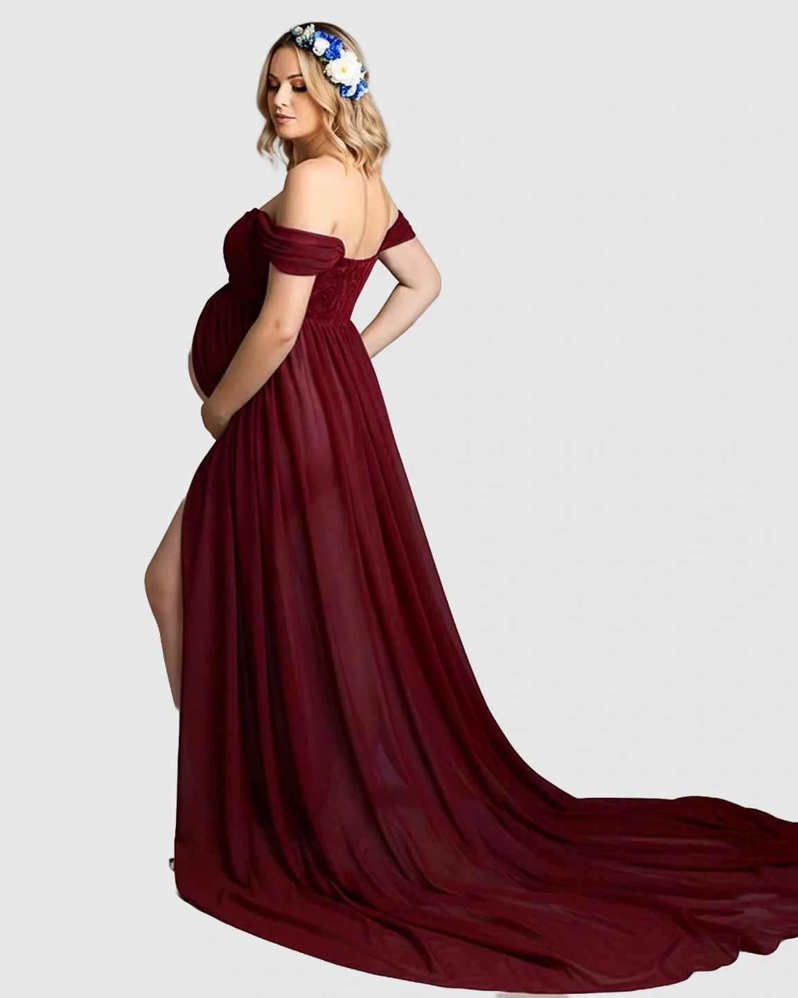 Pregnant woman in a flowing, off-shoulder burgundy chiffon maternity gown with a long train and thigh-high slit.