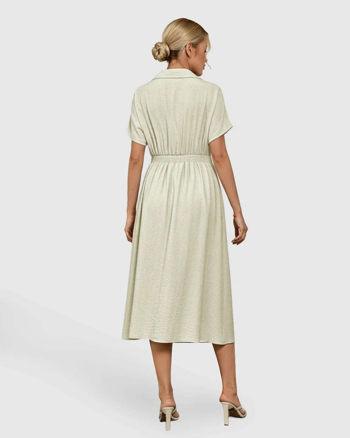 Blonde woman from behind wearing a light green lapel collar A-line maternity midi dress with a cinched waist.