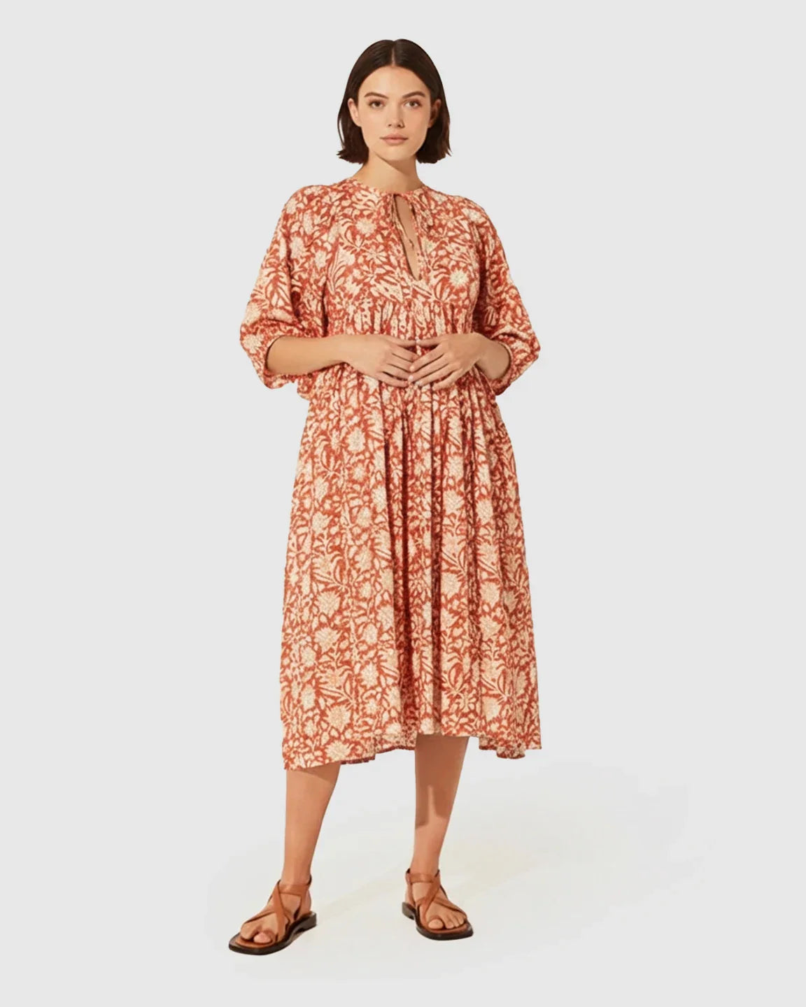 Woman in a loose-fit terracotta floral maternity midi dress with gathered shoulders and puff sleeves.