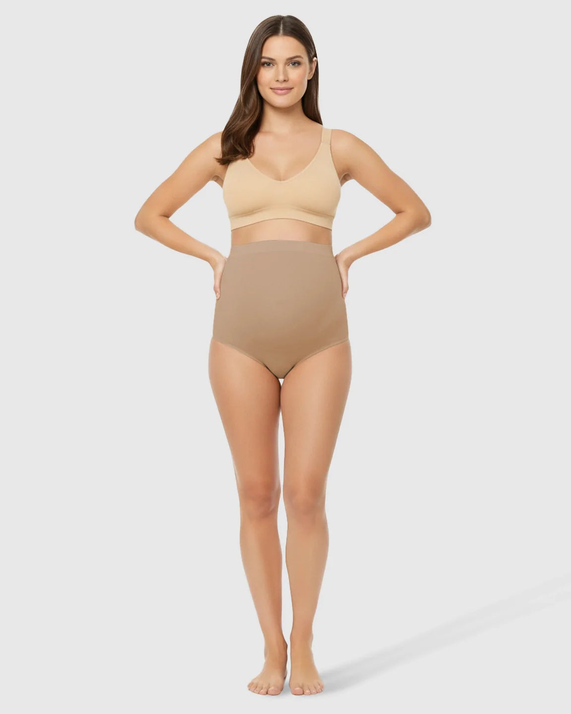 Woman models Bump Society high-waist seamless belly-support maternity underwear and matching bra in nude.