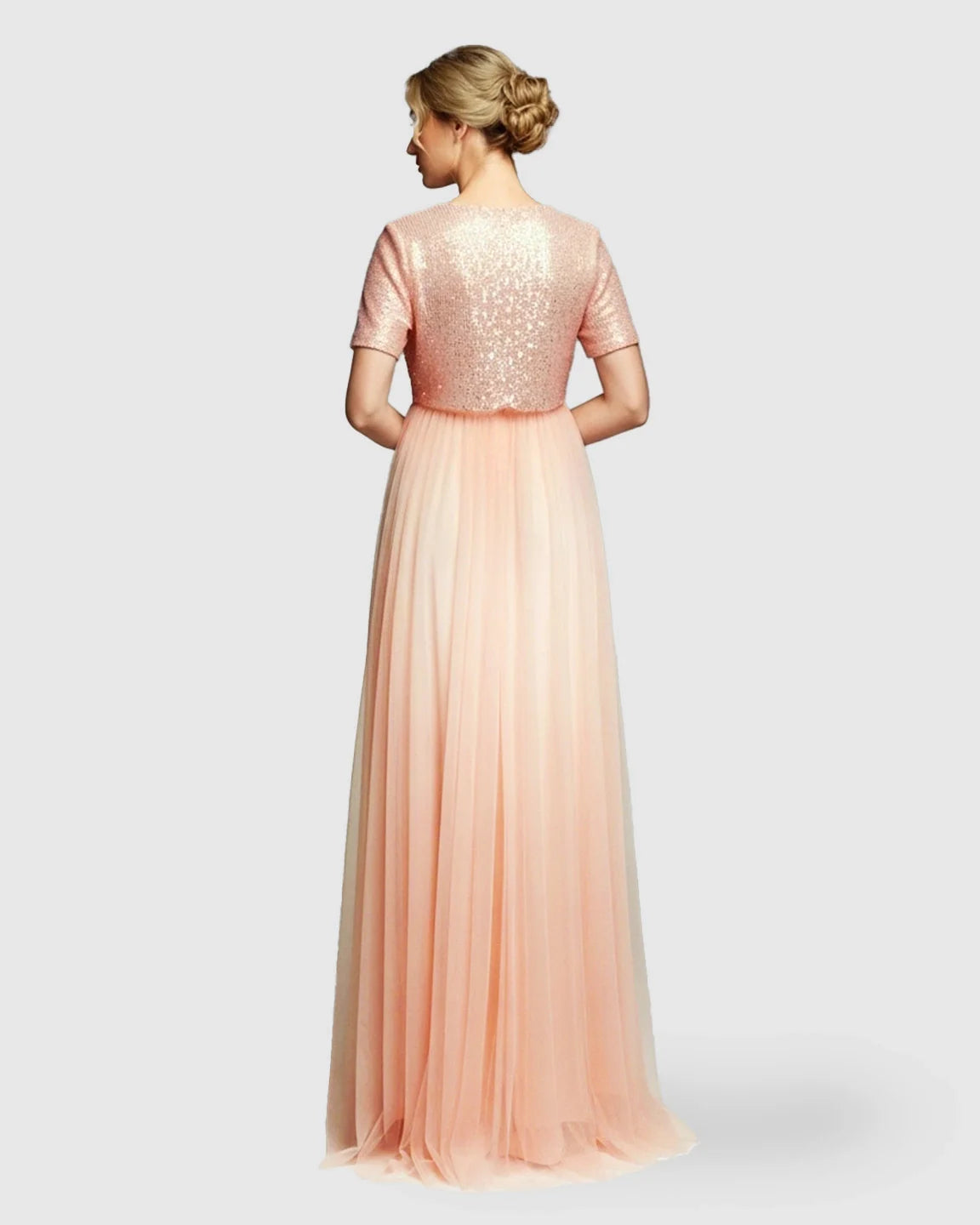 Back view of a pink sequin A-line maternity gown with short sleeves and a flowing mesh skirt.