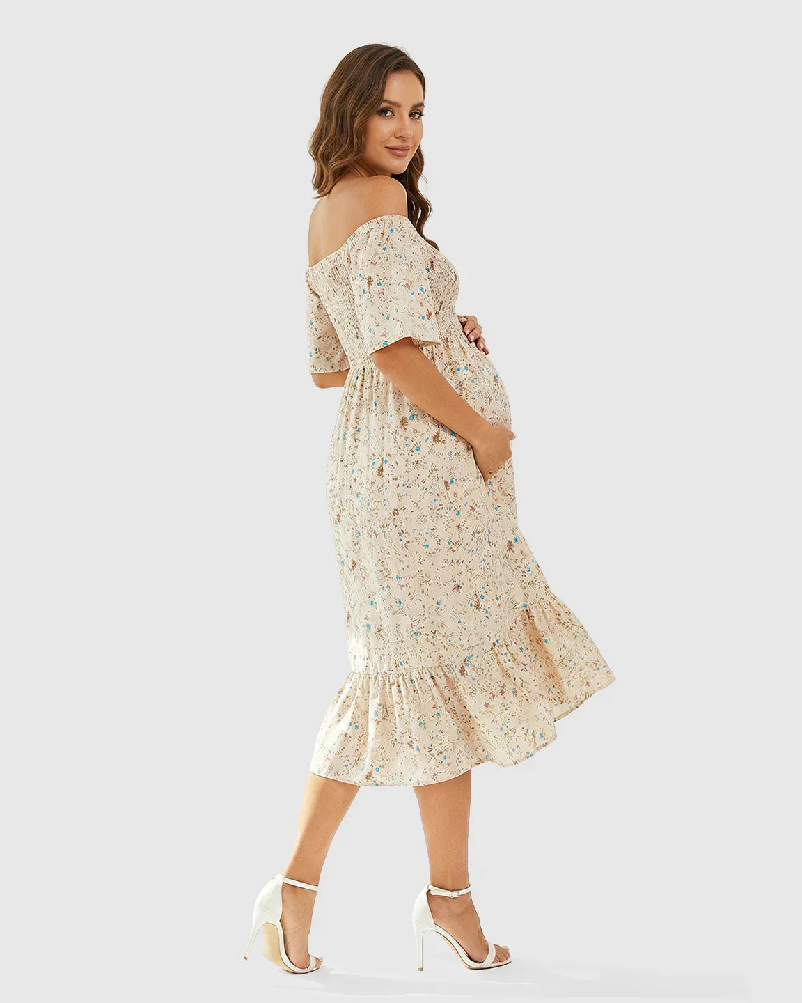 Pregnant woman in a beige floral off-shoulder smocked maternity midi dress with flutter sleeves and tiered skirt.